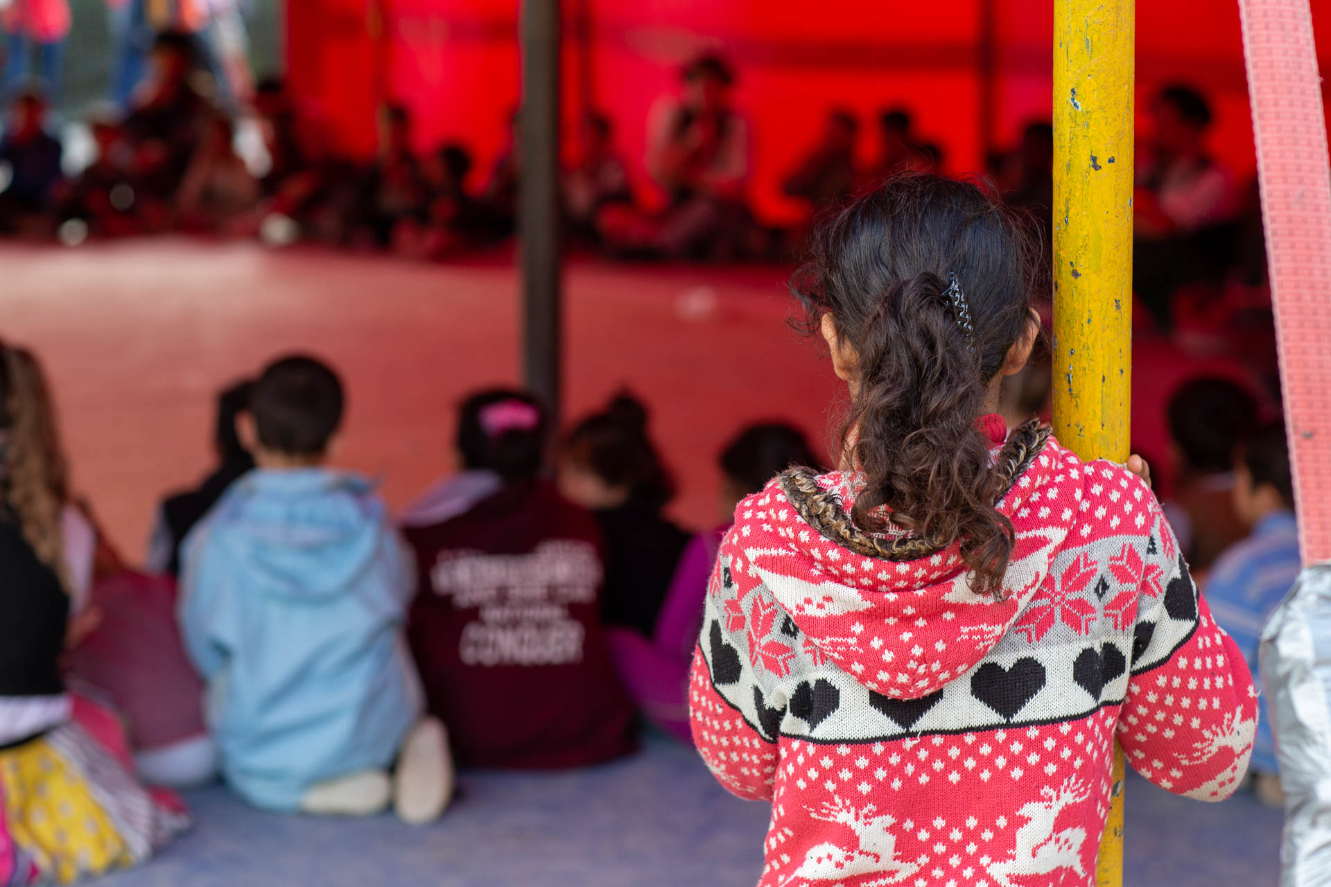 Girl standing at the edge of a big top circus tent set up in the refugee camp in Samos