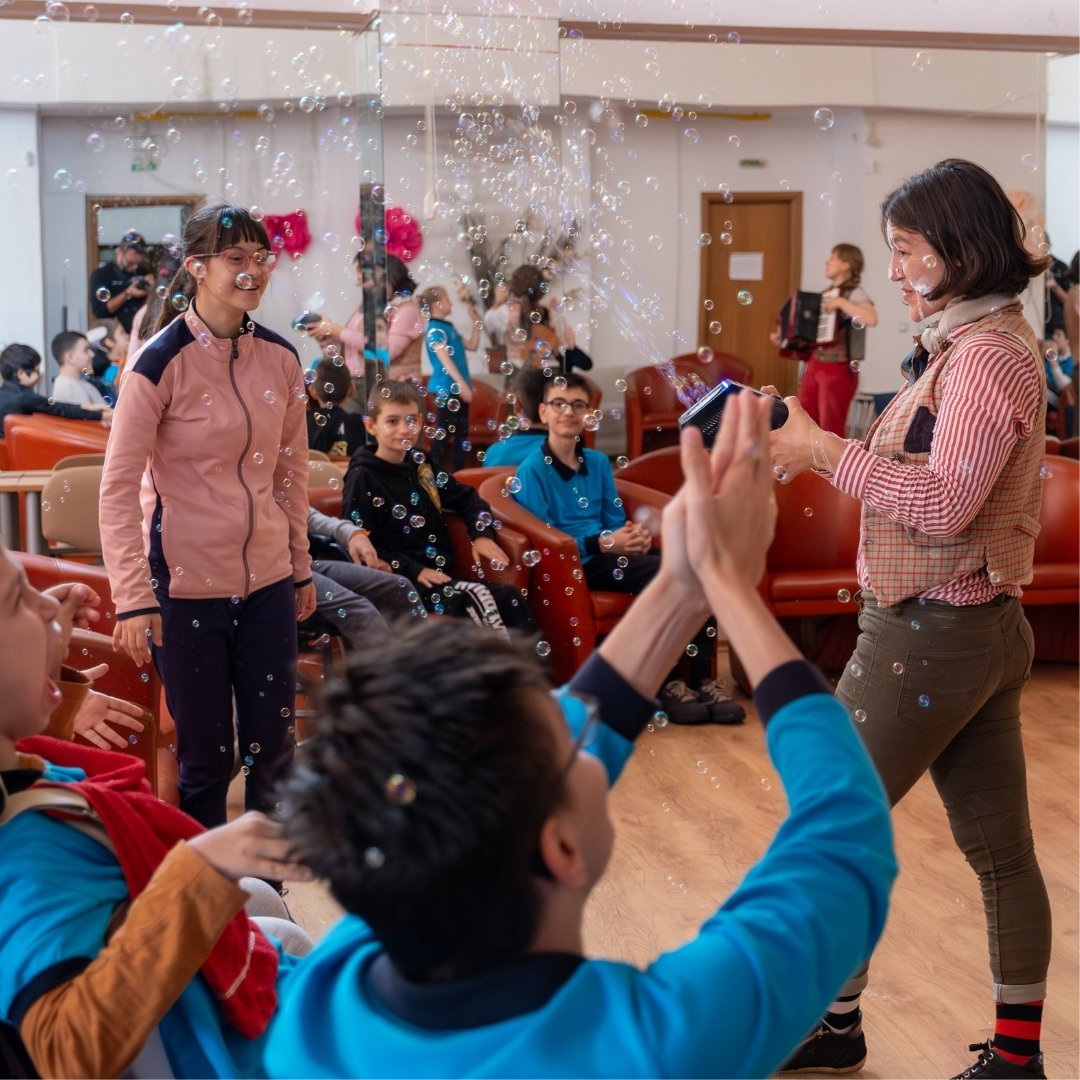 Children in a school for young people with disabilities laugh and smile as they play with bubbles during a Flying Seagull sensory circus workshop.