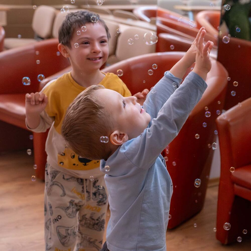 Children smiling as they play with bubbles during a Seagull sensory play session in a school for children with disabilities in Romania.